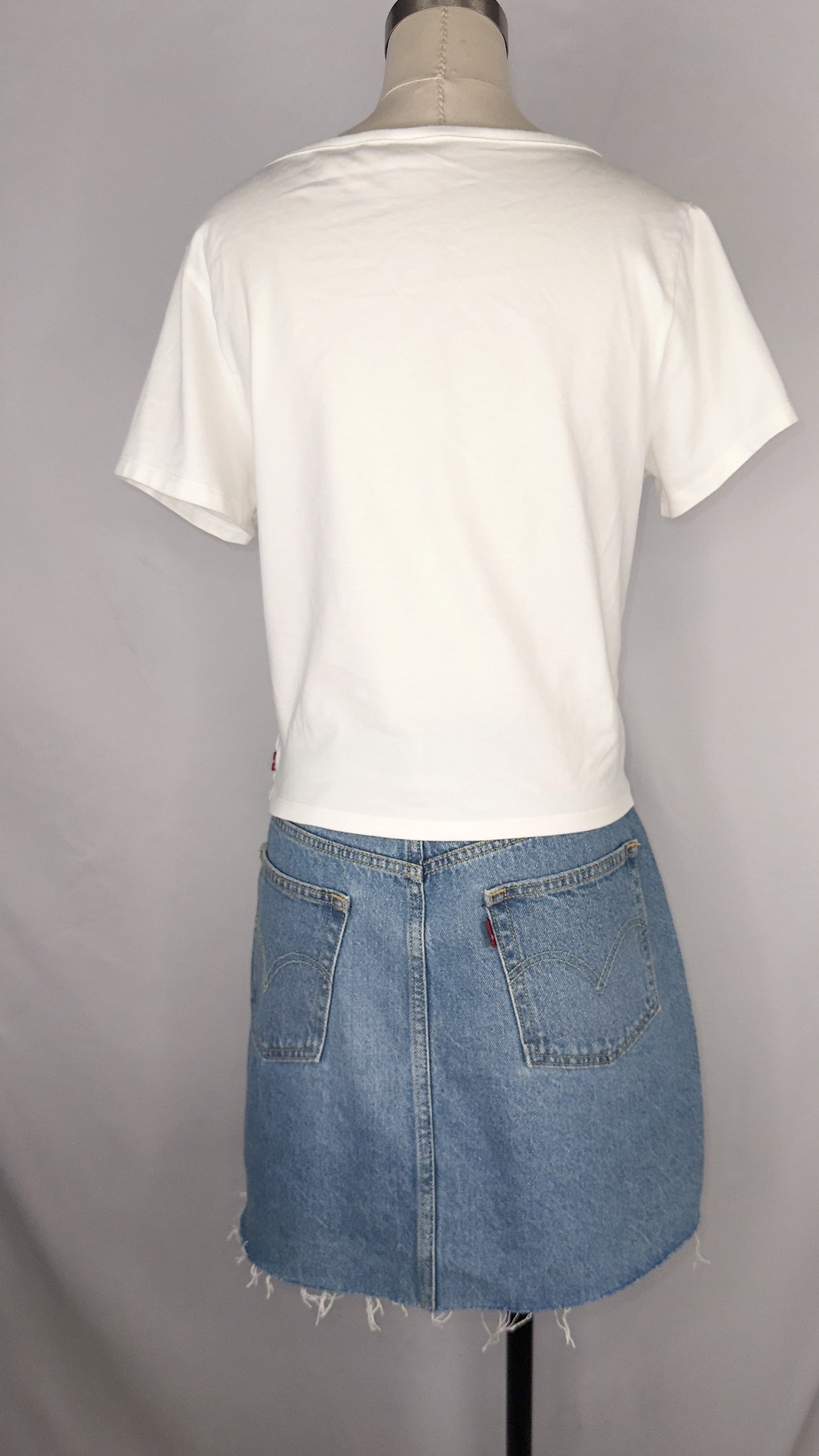 Back view of Levi's Corset T-Shirt in White with mannequin wearing a light blue distressed denim mini skirt.