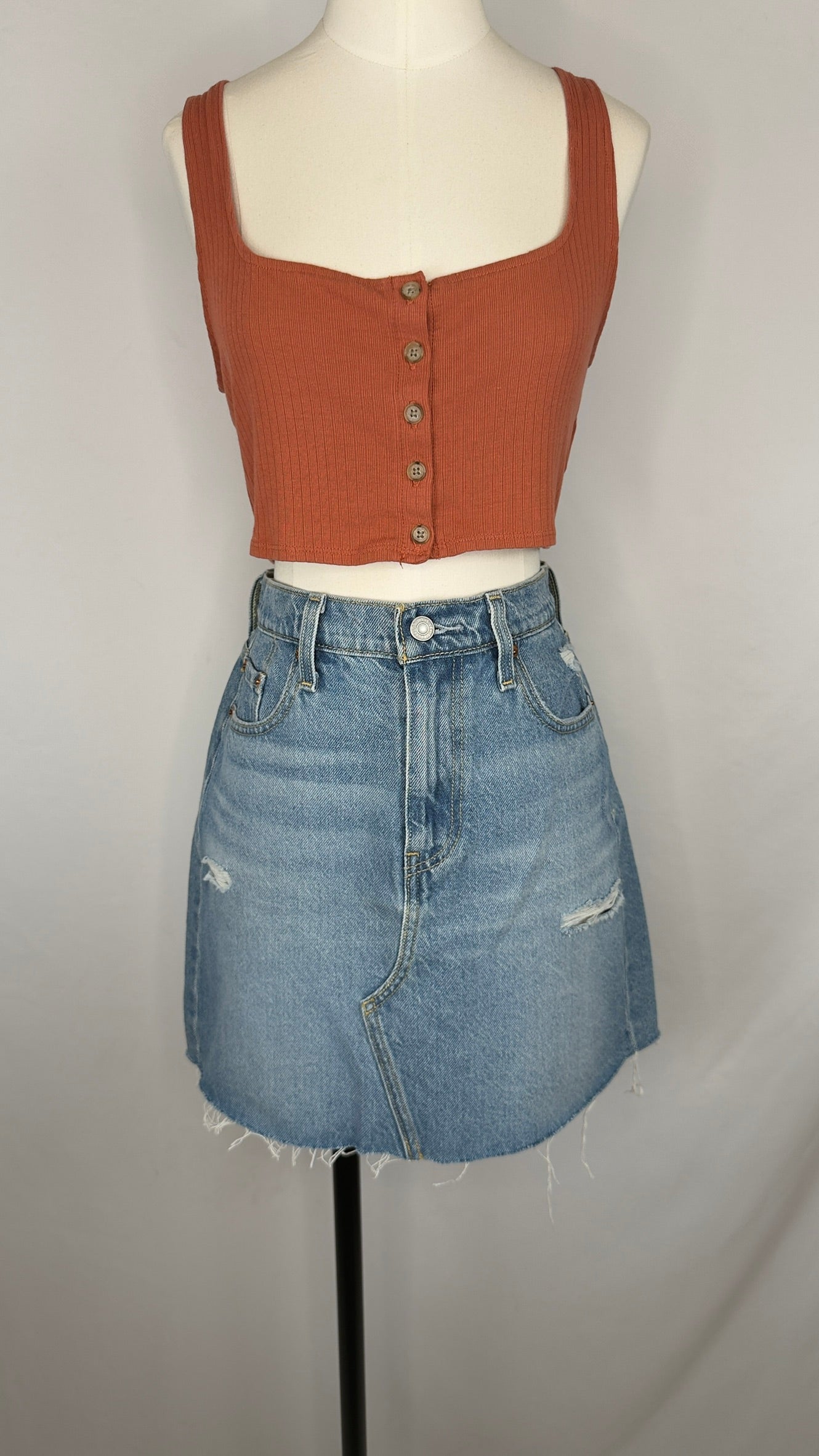 Mannequin wearing a rust-colored crop top and blue denim skirt on a plain background