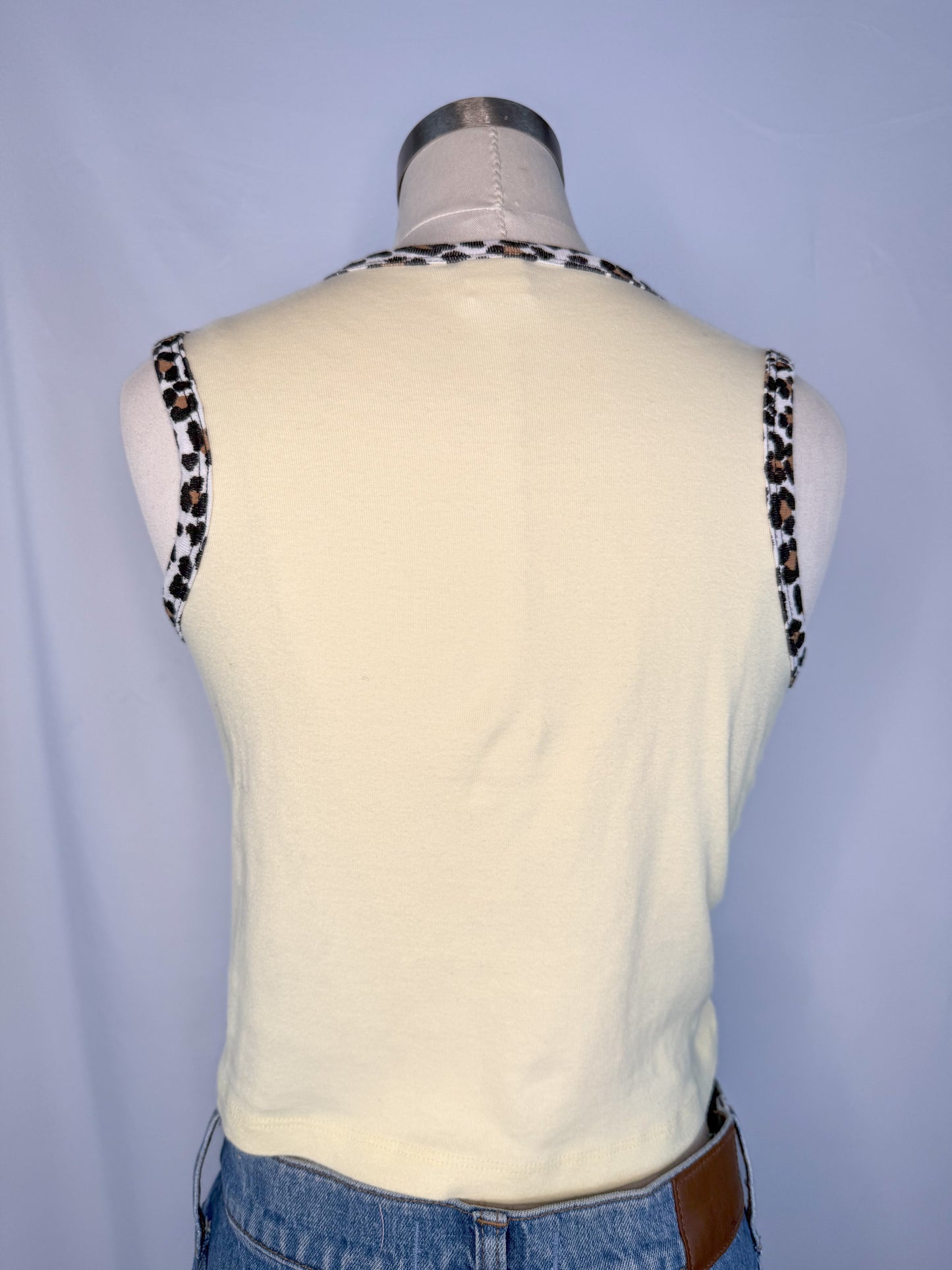 Back view of Urban Outfitters Feeling Groovy Crop Top in Yellow. Plain yellow backside with cheetah detail on the neckline and arm cutouts