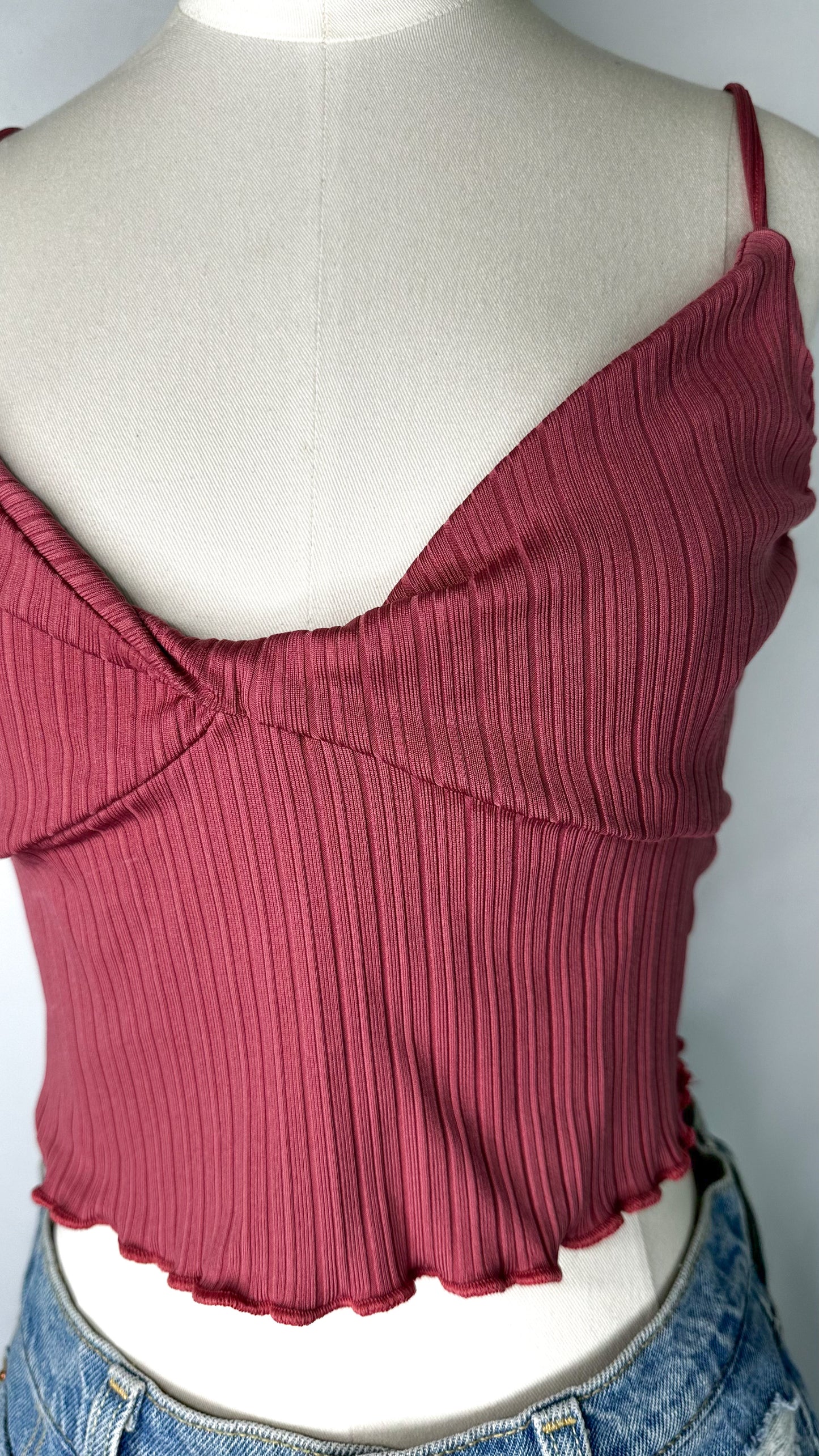 Up-close front view of Urban Outfitters Ribbed Twist Front Cami Top in Pink featuring the twist front and ribbed detailing, as well as the lettuce edge hem.