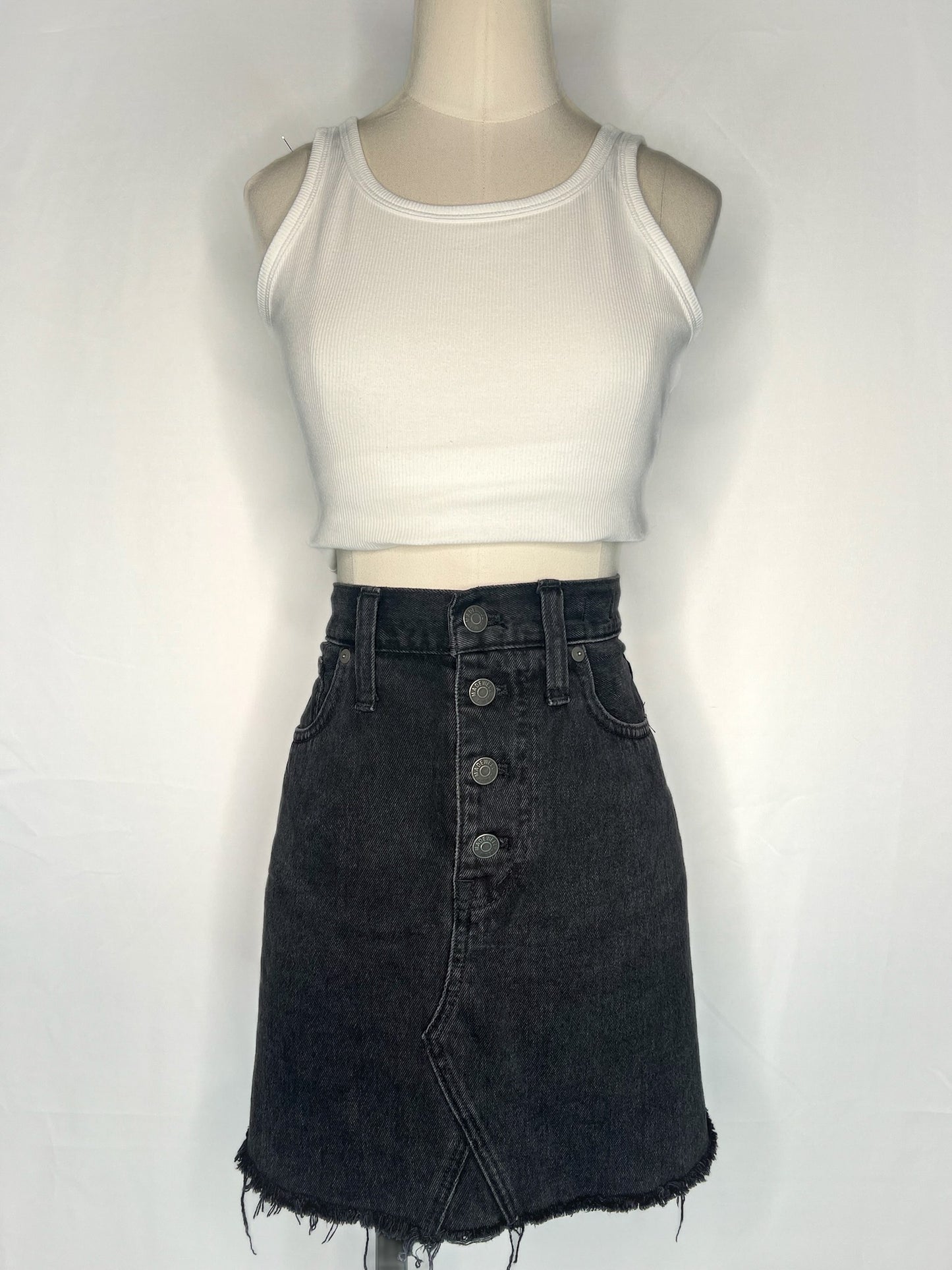 Full view of white crop top (shown for outfit purposes) and Madewell Rigid Denim A-Line Mini Skirt in Lunar Wash: Button-Front Edition.