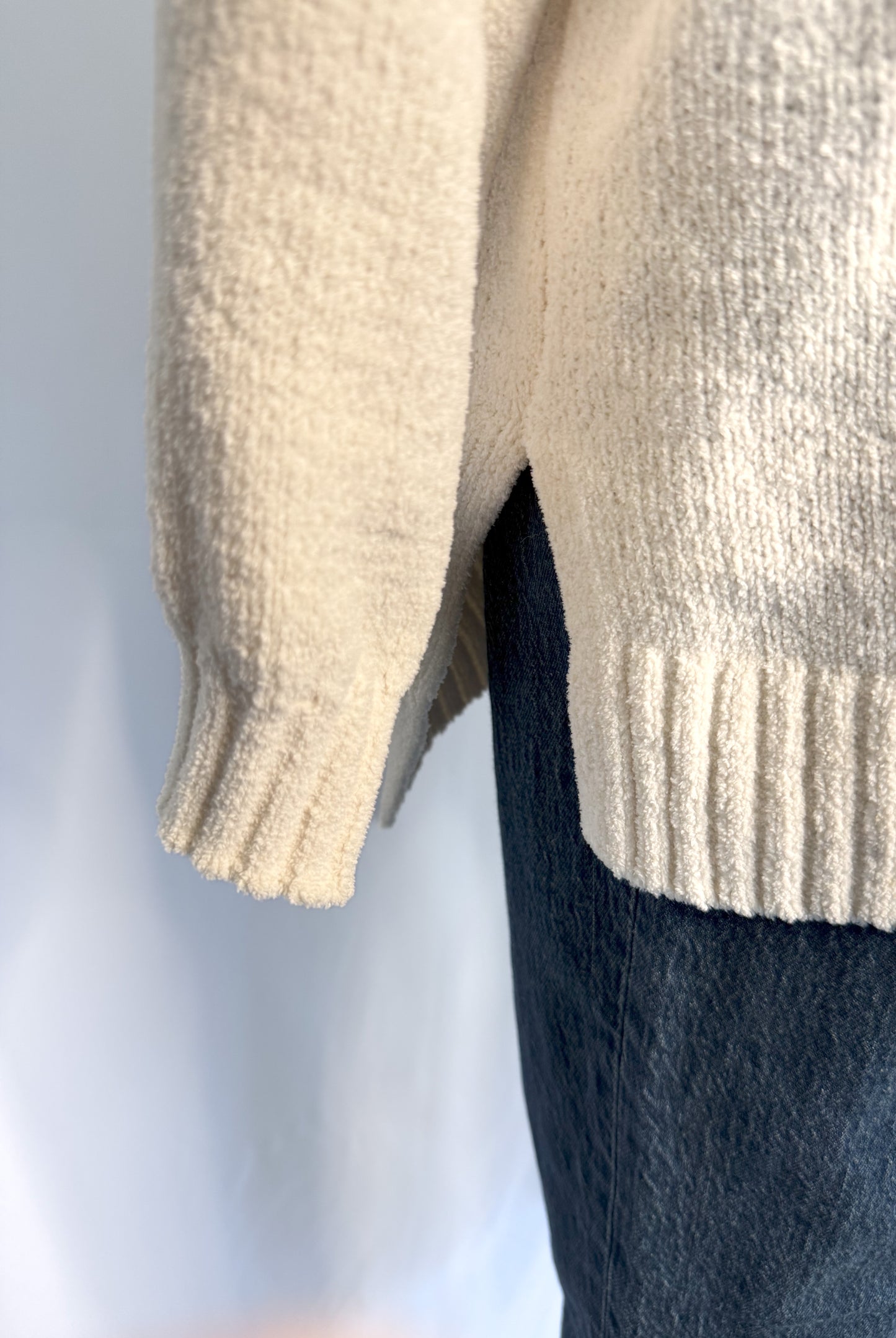 Bottom side view of American Eagle Oversized Rainbow Stripe Sweater in Cream featuring a split side hem.