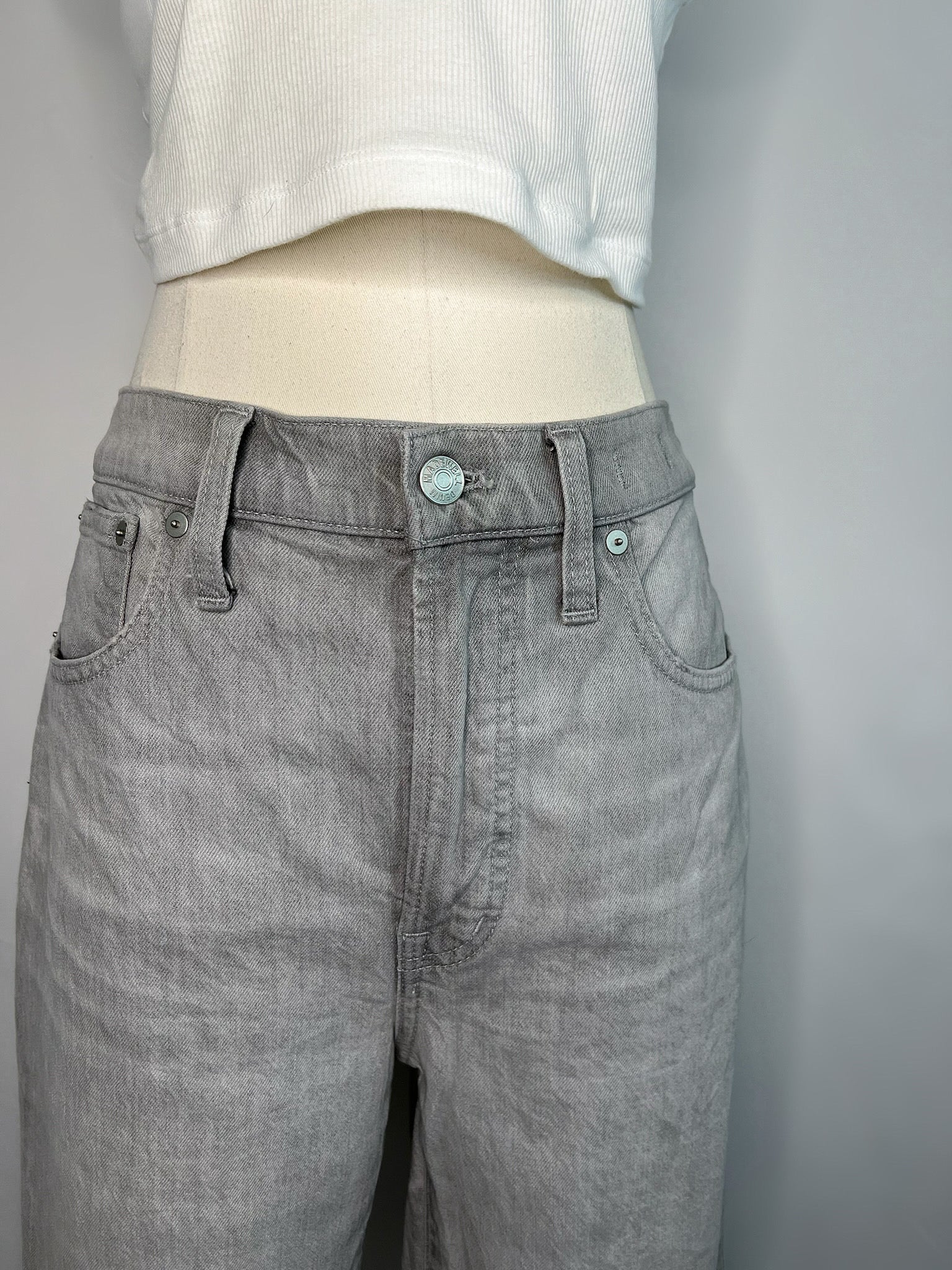 Close up of front of grey Madewell slim demi-boot jeans