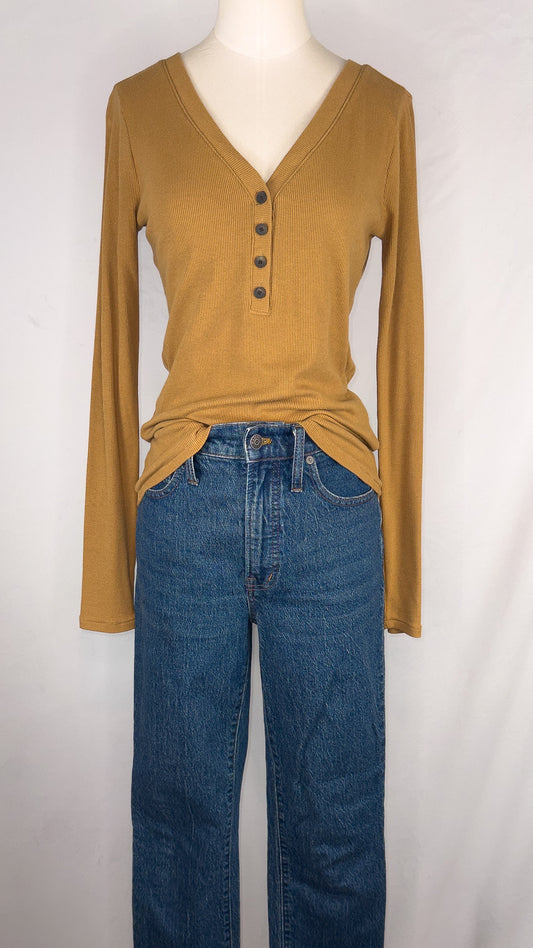 Front view of Madewell Fine Ribbed Henley Tee in Toffee. Featuring long sleeves and a four button v-neckline. Top is paired with a dark blue straight leg jean.
