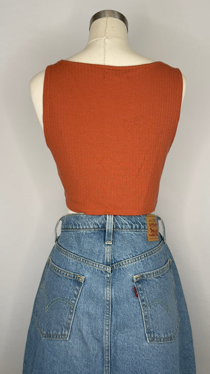 Mannequin wearing a rust-colored sleeveless top and blue jeans on a white background.