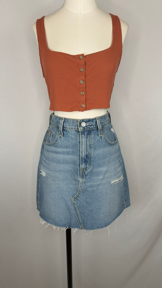 Mannequin wearing a rust-colored crop top and blue denim skirt on a plain background