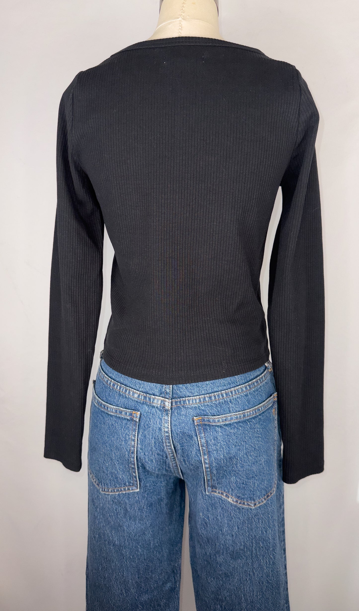 Back view of Madewell Square-Neck Long-Sleeve Crop Tee in True Black. The plain backside of the shirt is shown, along with the dark blue jeans.