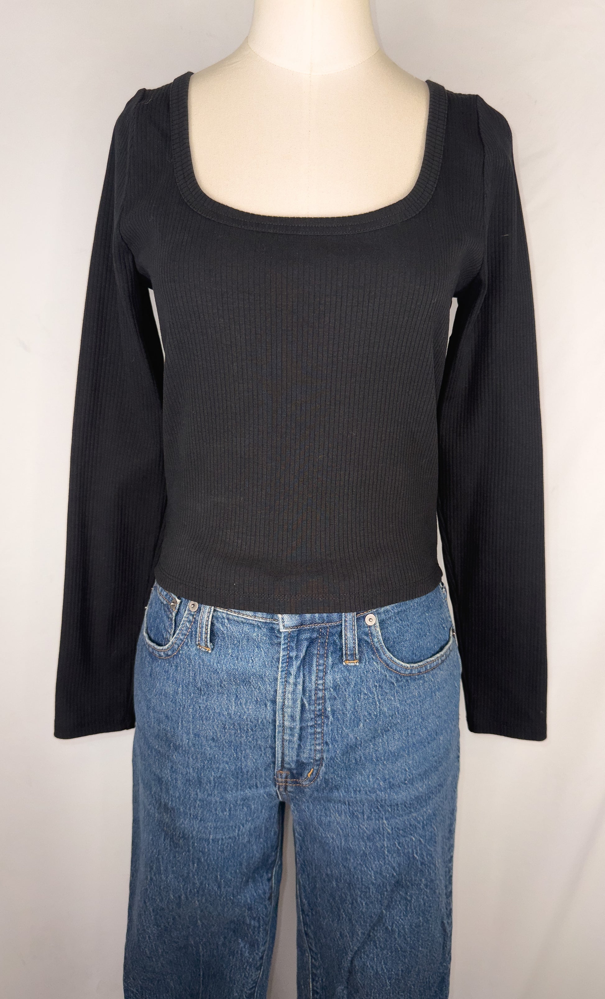 Front view of Madewell Square-Neck Long-Sleeve Crop Tee in True Black. Plain black long sleeve ribbed tee with a square neckline. The top is shown on the mannequin paired with a dark blue jean.