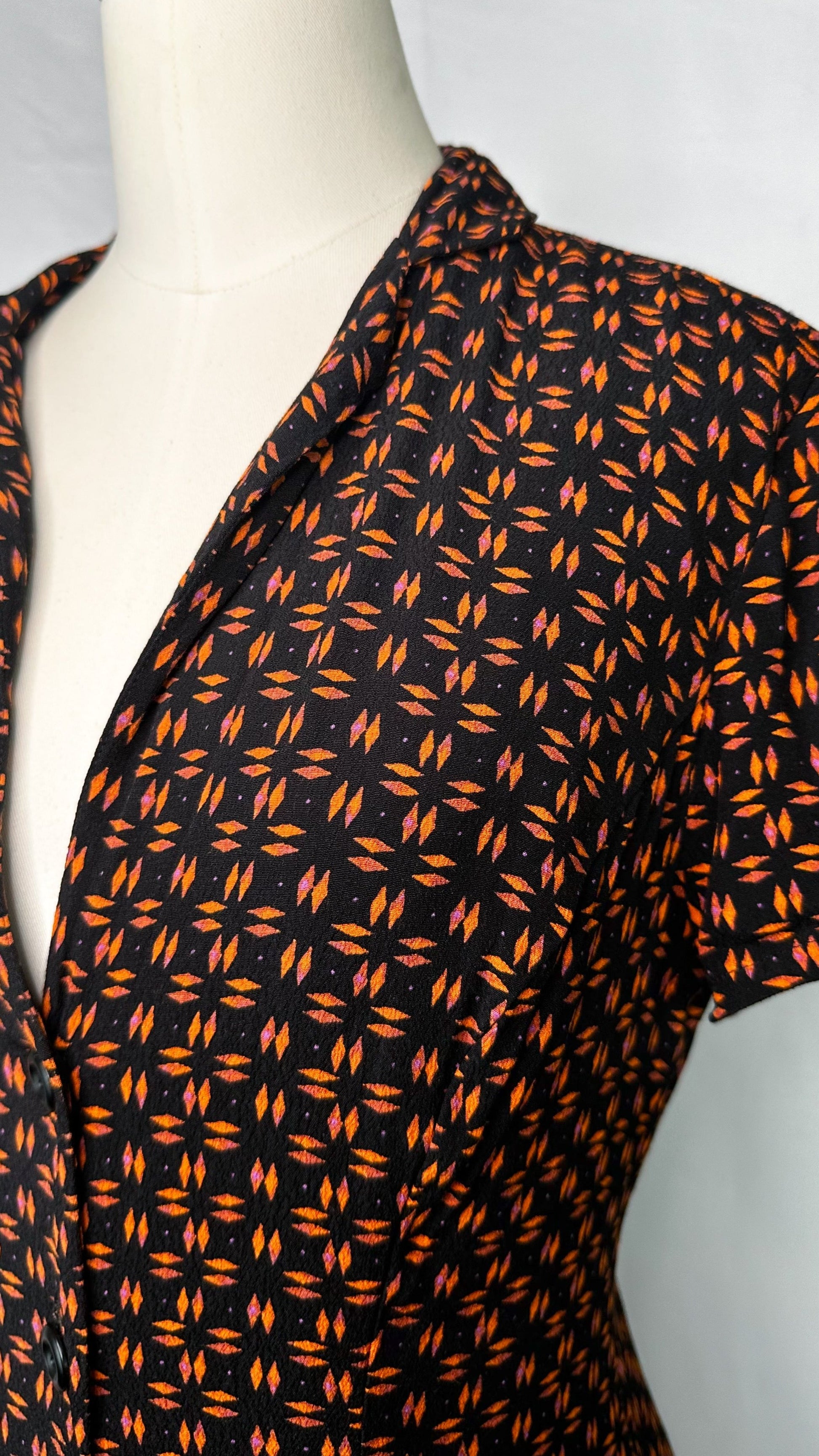 Angled, close-up view of Silence + Noise Button-Down Mini Dress in Retro Print featuring the low-cut neckline and collar.