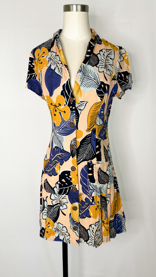 Front view of Silence + Noise Button-Down Mini Dress in Tropical Print size medium, featuring two pockets and wood-like buttons all the way down the dress.