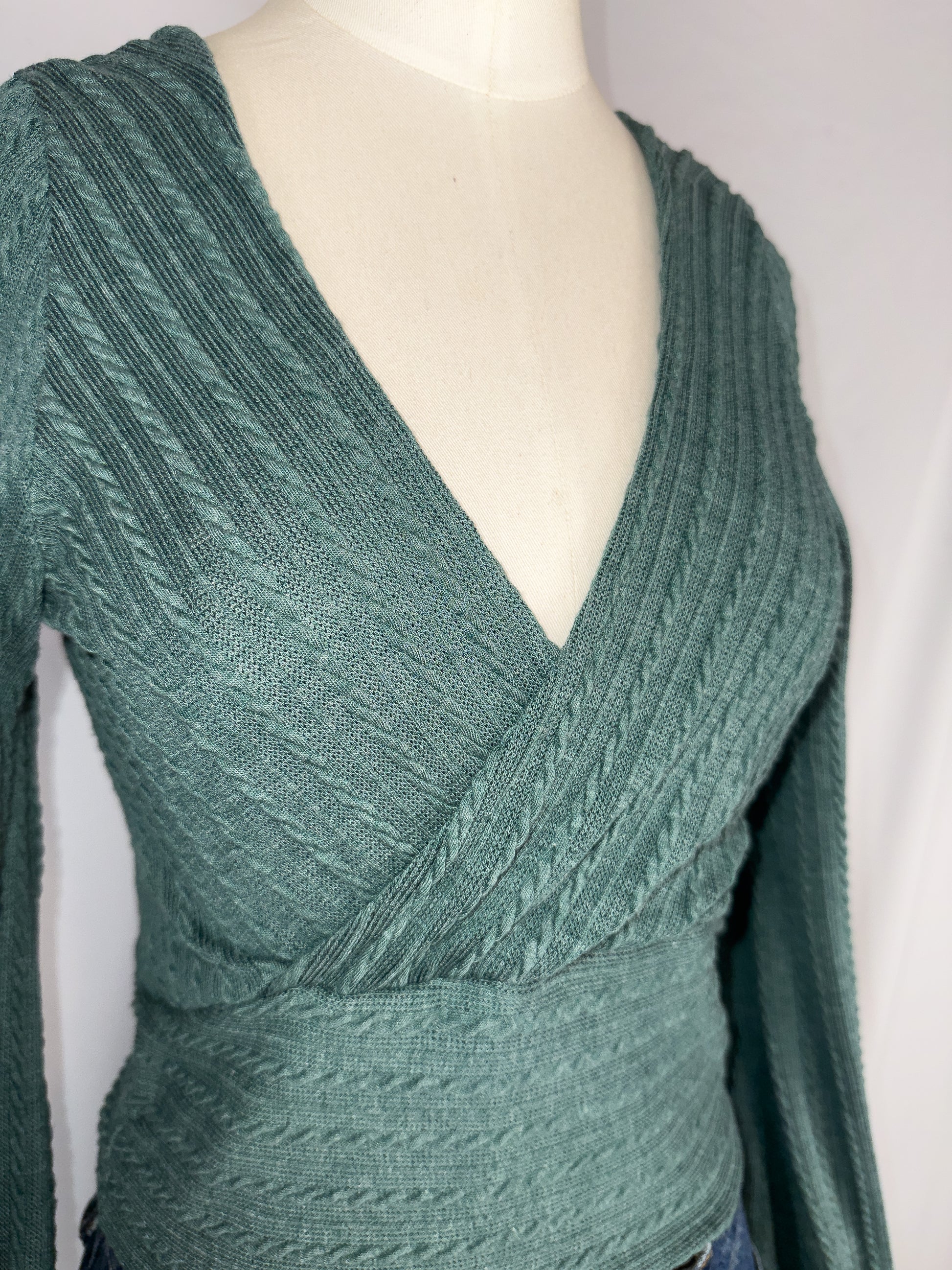 Up-close side angle view of ZAFUL Ribbed Knit Cropped Wrap Top in Green. Featuring the knit detailing as well as the faux wrap feature on the front.
